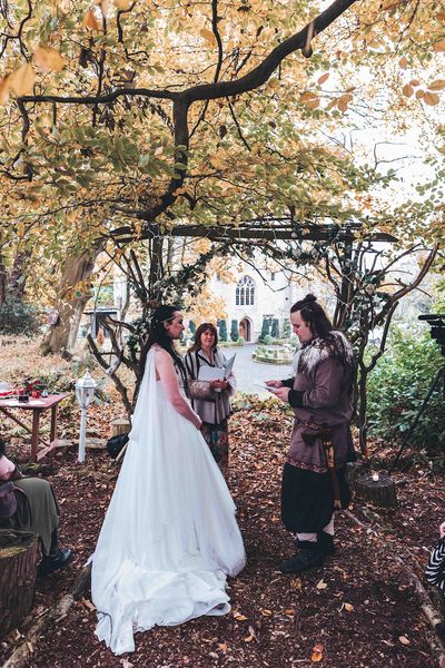 Couple taking vows at Viking-themed woodland wedding at Langley Castle, Northumberland