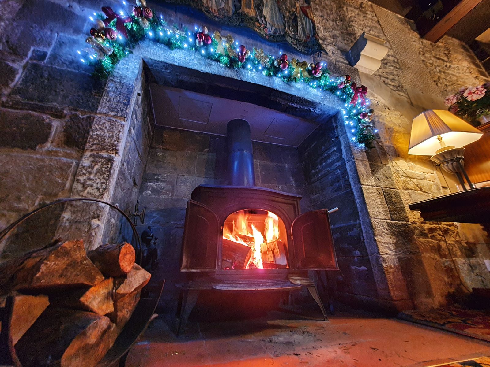 Fireplace and roaring log fire in the Langley Castle drawing room, Northumberland, UK.