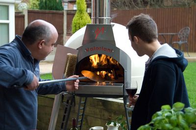 Orchard Ovens owner, Andrew Manciocchi, loading pizza into a Fornino 60 wood-fired oven