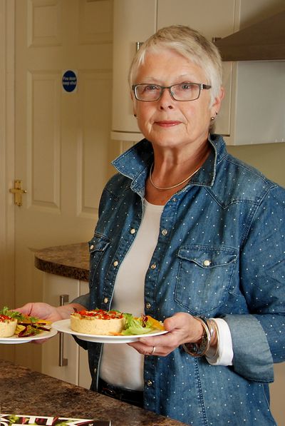 Woman holding two plates of vegetarian quiche