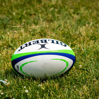 Rugby ball sitting on a rugby field ready for play.