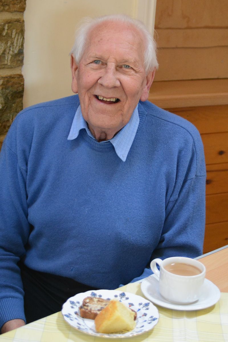 Man eating vegetarian cake, with a cup of tea