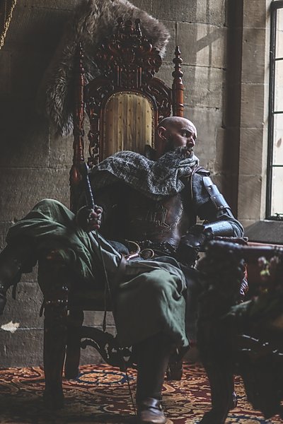 Man in the drawing room 'king chair' of Langley Castle Hotel, Northumberland, UK.