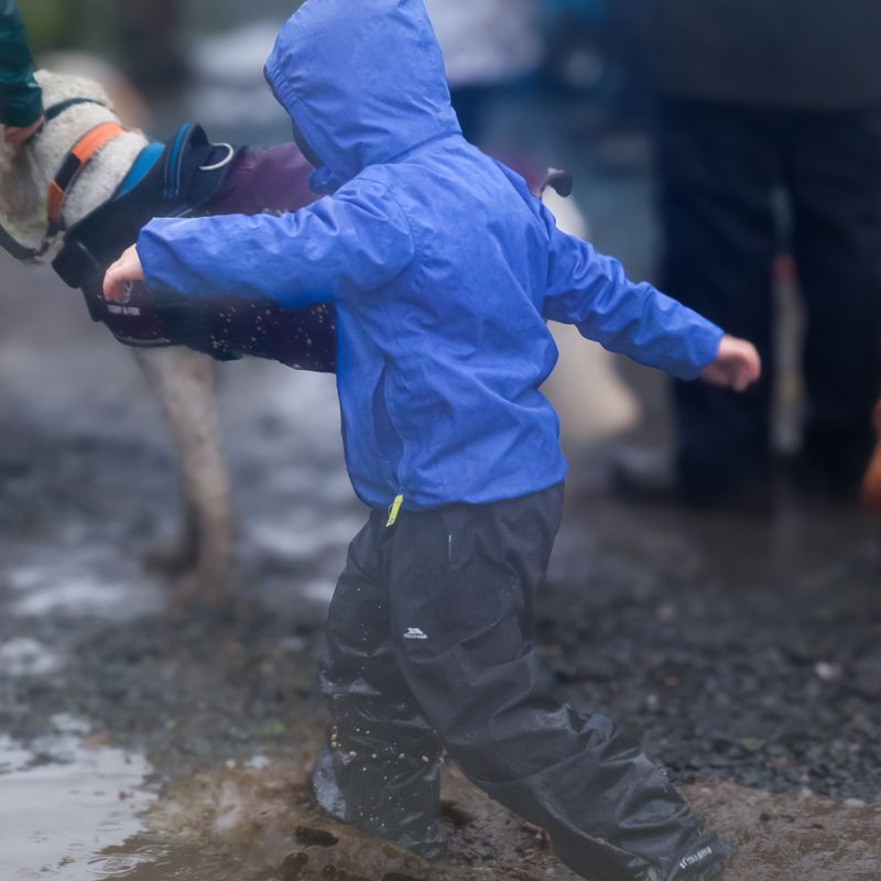 A child jumps through the mud and puddles at Grasmere Lakeland Sports and Show 2024.