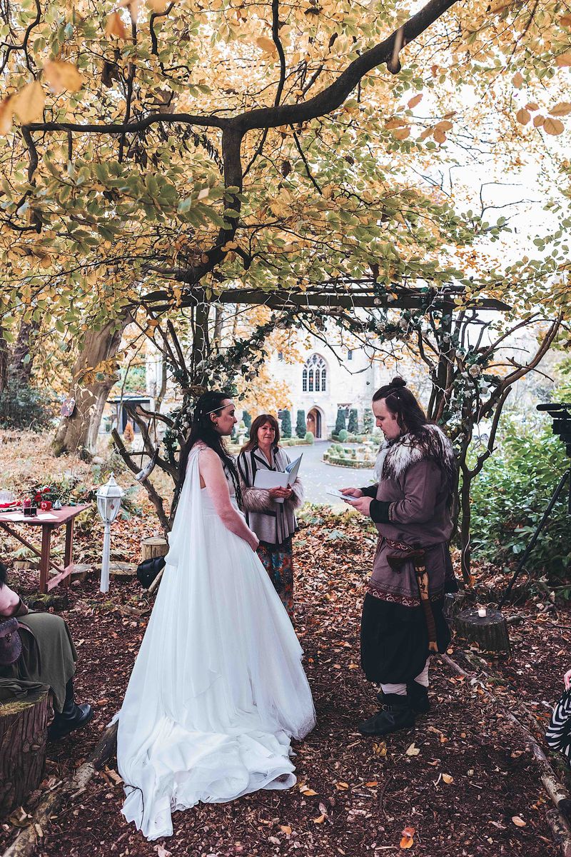 Couple taking vows at Viking-themed woodland wedding at Langley Castle, Northumberland