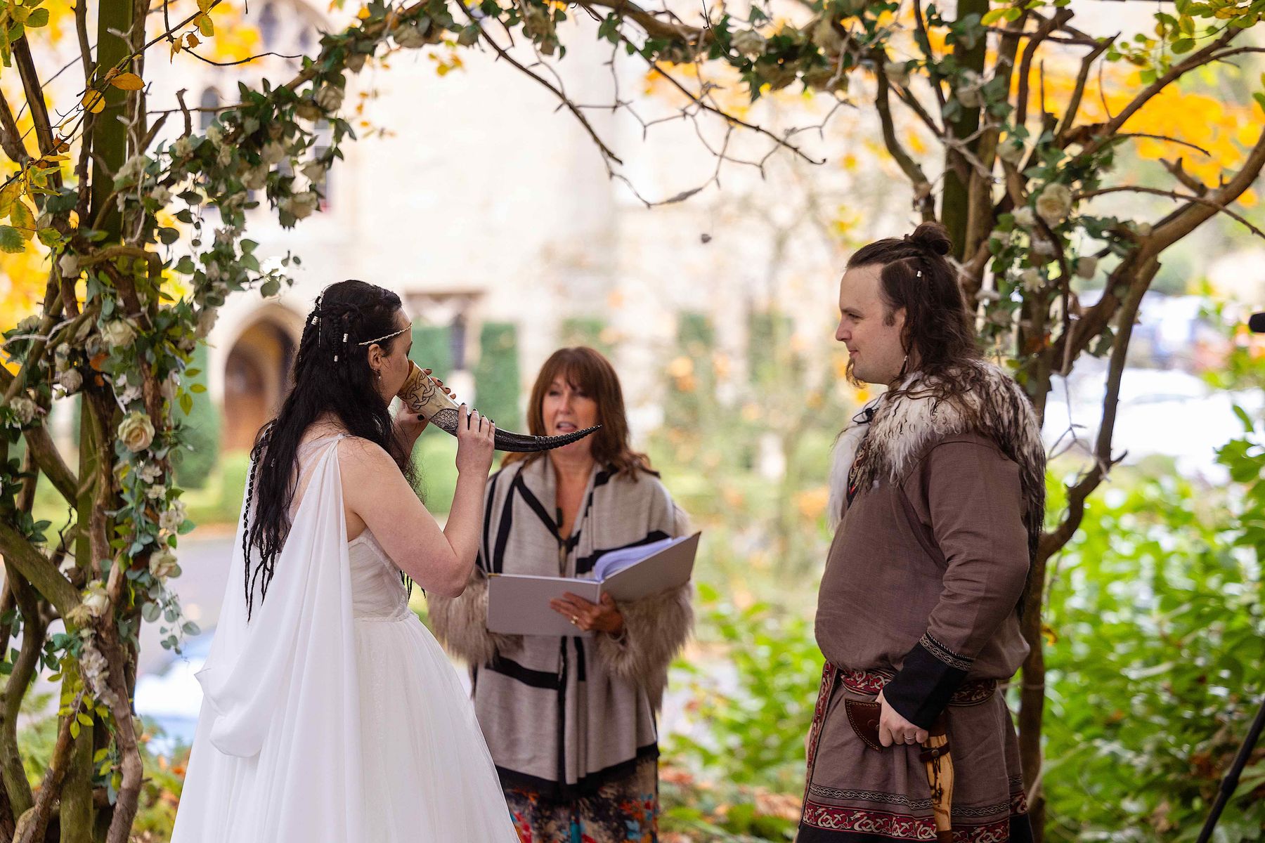Bride places horn to her lips in Viking wedding at Langley Castle, Northumberland