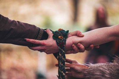 Benjamin and Annmarie Coomber's hands are tied together in a Viking hand fasting ceremony at their wedding at Langley Castle, Northumberland