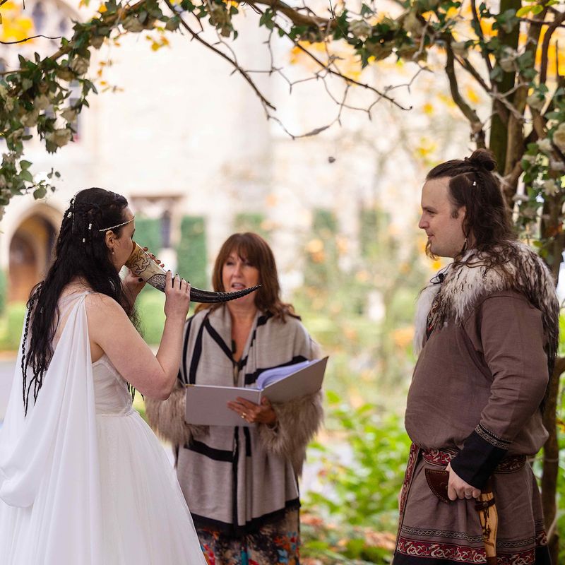 Bride places horn to her lips in Viking wedding at Langley Castle, Northumberland