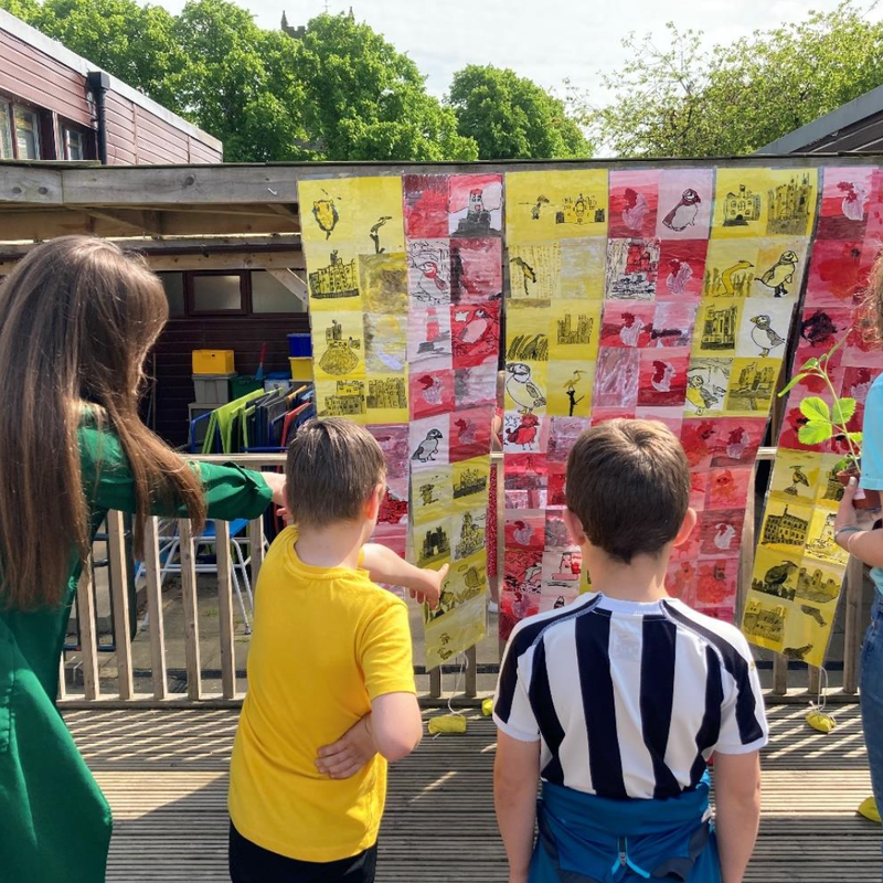 The special flag created by Stannington First School pupils for Northumberland Day 2023, featuring their own artwork, hanging outside.