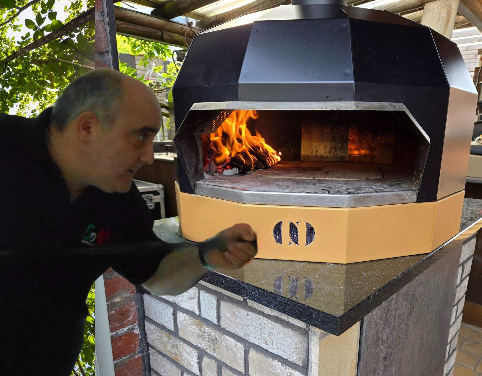 Pizza oven pioneer, Andrew Manciocchi, checks the flame inside the new Orchard Ovens Fornino 50 pizza oven, new for 2025.