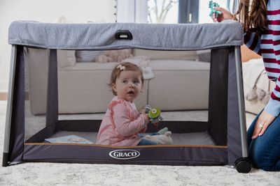 Graco FoldLite Travel Cot pictured with child playing in the cot 