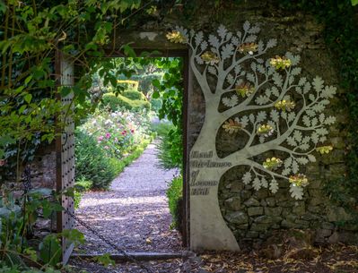 Looking through a gate from the Levens Hall garden, which now has the head gardeners' commemorative tree sculpture beside the gate.
