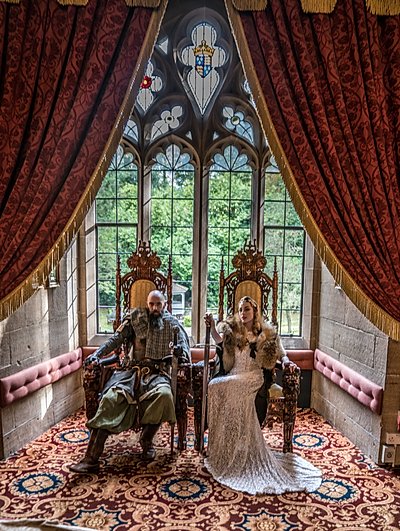 Couple on the throne chairs, in front of the drawing room window at Langley Castle 