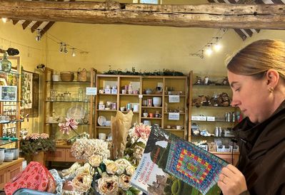 Person browsing Kaffe Fassett's 2026 book in Levens Hall and Gardens gift shop