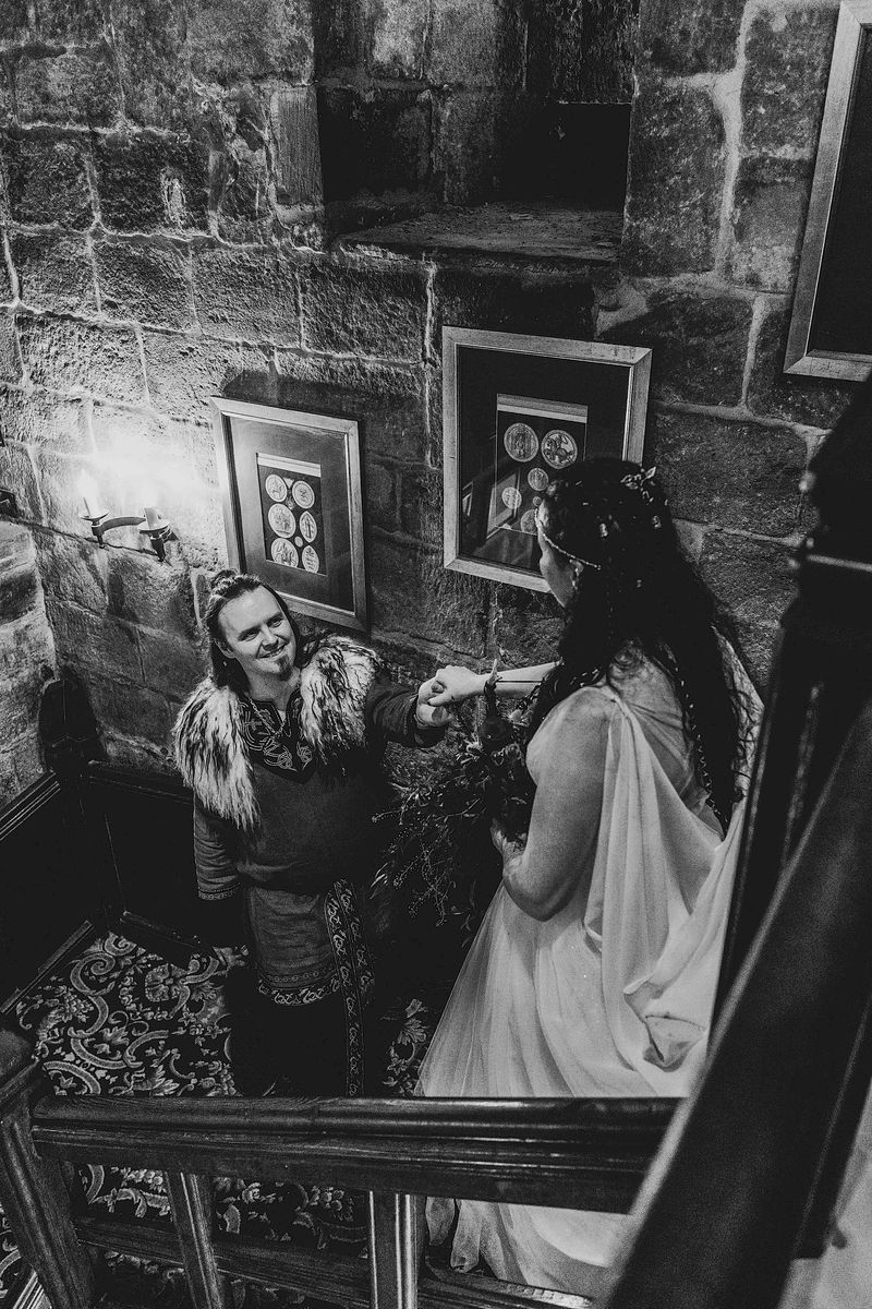 Benjamin helps wife, Annmarie Coomber, down the grand staircase of medieval Langley Castle, Northumberland, on the day of their Viking wedding